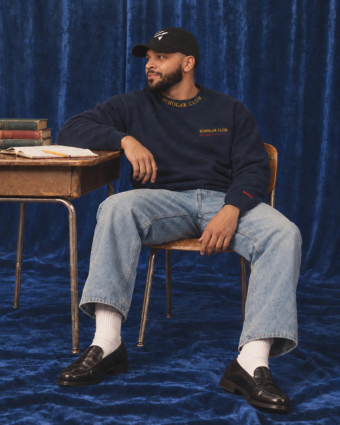 Cherokee A. Moore wearing a Scholar Club crewneck beside a school desk